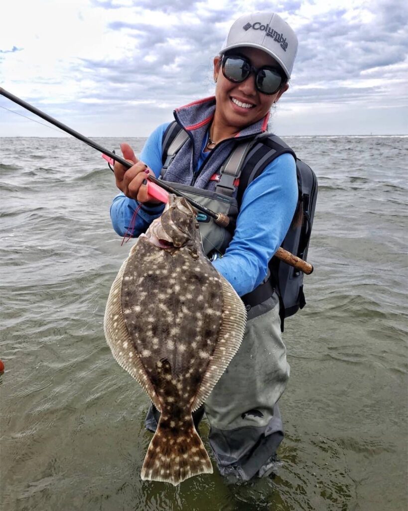 a woman poses with freshly caught flounder